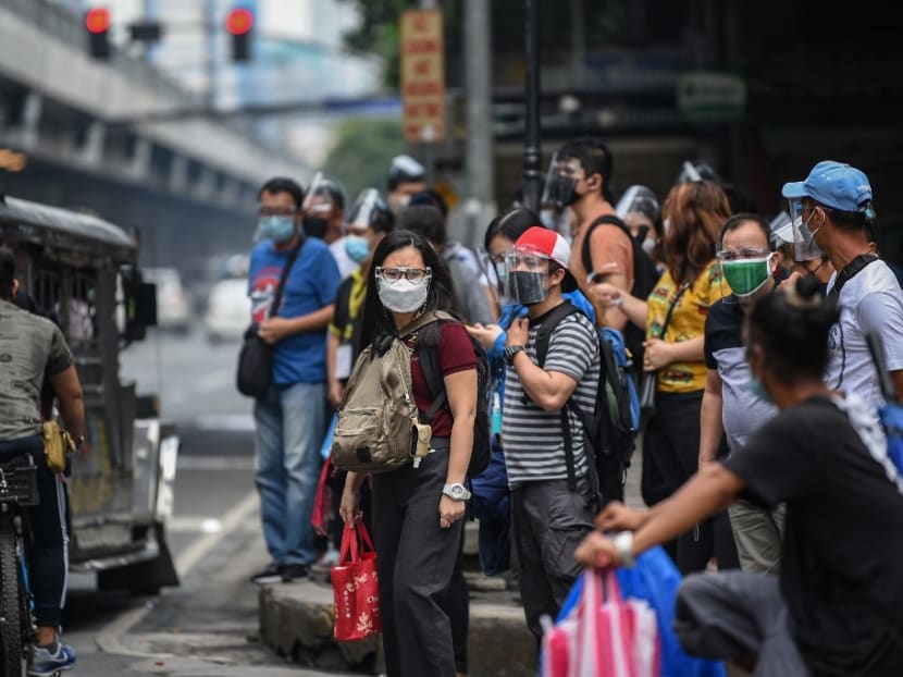 People wearing face masks and shields to protect themselves against the Covid-19 coronavirus wait for their transport on a street in Manila on Sept 7, 2021, a day before the authorities lift a stay-at-home order amid record infections fuelled by the contagious Delta variant.