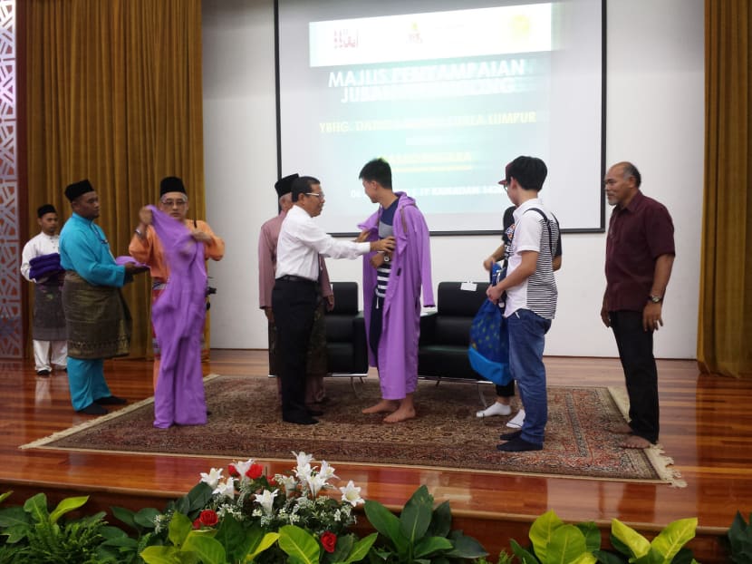 Kuala Lumpur Mayor Ahmad Phesal Talib (centre left, in white) helping a tourist don a robe at the National Mosque. Photo: The Malaysian Insider