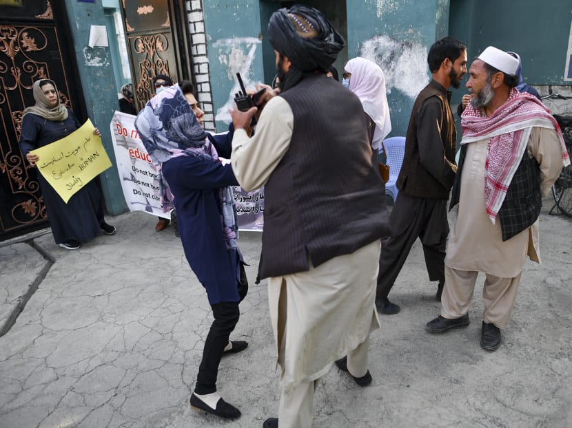 A woman protestor scuffles with a member of the Taliban during a demonstration outside a school in Kabul on Sept 30, 2021.
