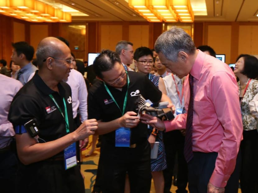 Prime Minister Lee Hsien Loong tries on a robotic glove designed to help rehabilitate upper limb functions in post-stroke patients. Photo: Mr Lee's Facebook page/Ministry of Communications and Information