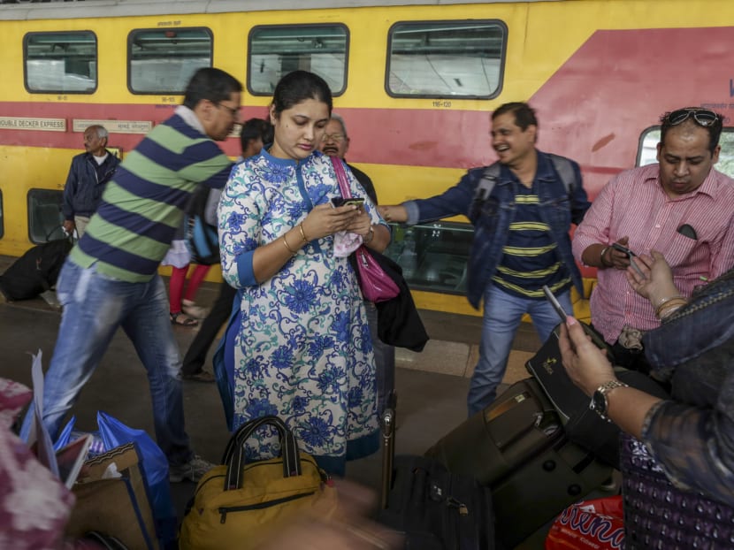 Commuters looking at their phones at a train station in Mumbai, India. Google has launch Neighbourly, a hyper-local social network that lets people share local expertise and crucial information with others in the vicinity.