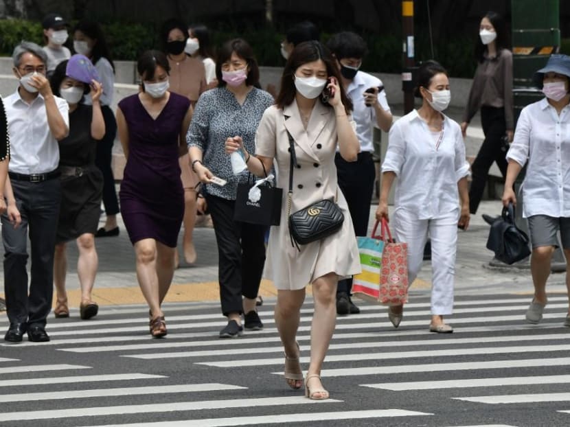 Pedestrians wearing face masks cross the road in central Seoul on June 23, 2020.