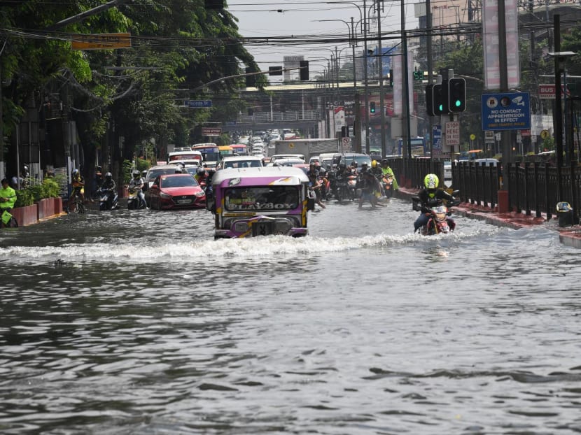A passenger jeepney and a motorist traverse on a flooded road after heavy downpour brought about by southwest moonson hit Manila on Aug 14, 2023.