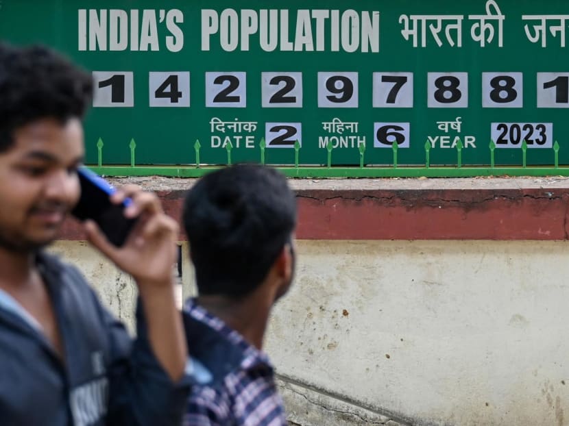 Pedestrians walk past a population clock board displayed outside the International Institute for Population Sciences (IIPS) in Mumbai on June 2, 2023.