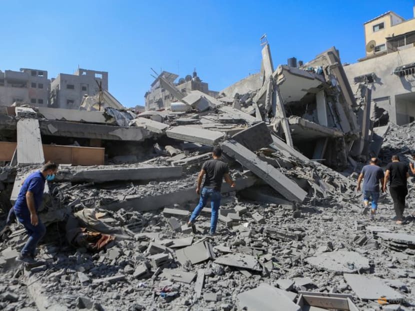 Palestinians walk past the rubble of houses following Israeli strikes in Gaza City on Oct 15, 2023.
