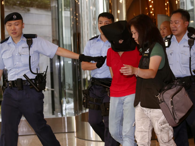 A female suspect is arrested by police officers after a woman opened fire and wounded four people at a park in Hong Kong on Tuesday, June 26.