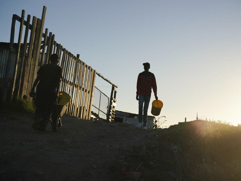 Residents collect water from a communal tap in a settlement outside of Cape Town.