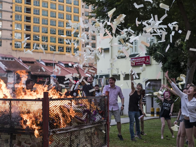 Staff of KTV pub Club FML at Prinsep Street throw joss paper into the air after performing the ritual of burning offerings to wandering spirits during the Hungry Ghost month. The pub typically spends between S$1,000 and S$2,000 on these paper offerings. Photo: Nuria Ling/TODAY