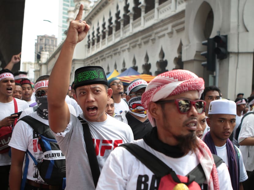 Many who attended the rally wore traditional Malay attire, with the males wearing a headpiece known as a “tanjak”, typically adorned by Malay warriors. Others carried flags inscribed with Quranic verses. Many who attended the rally wore traditional Malay attire, with the males wearing a headpiece known as a “tanjak”, typically adorned by Malay warriors. Others carried flags inscribed with Quranic verses.