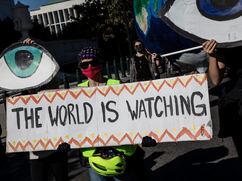 Climate activists hold signs and chant slogans during a protest over the 2020 Presidential Election in Washington, DC on Nov 4, 2020.
