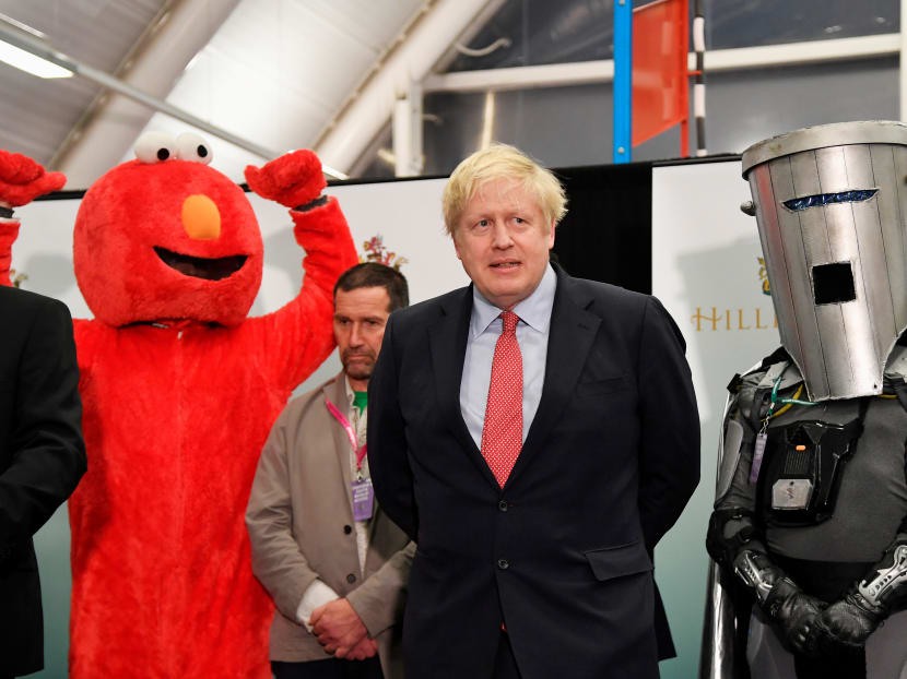 British Prime Minister Boris Johnson after winning his seat of Uxbridge and South Ruislip in Britain's general election, flanked by a man dressed as Sesame Street character Elmo and Lord Buckethead, a self-proclaimed satirical political character. Both stood as candidates in the election.