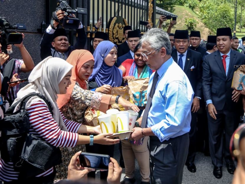 Yang di-Pertuan Agong Al-Sultan Abdullah Ri'ayatuddin Al-Mustafa Billah Shah (centre) distributes food from McDonald's to members of the Malaysian media at Istana Negara late last month.