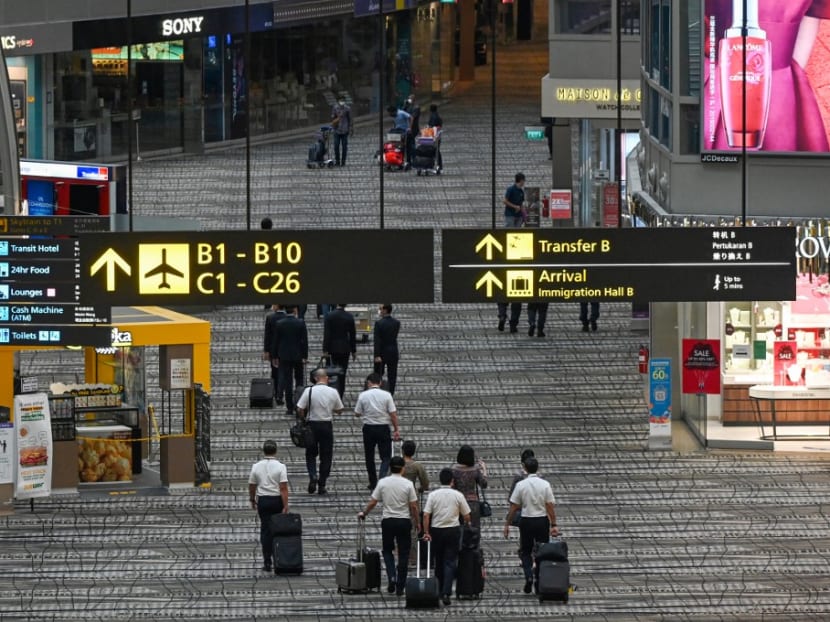 Singapore Airlines crew members and travellers walk along the transit hall of Changi International Airport terminal in Singapore on Jan 14, 2021.