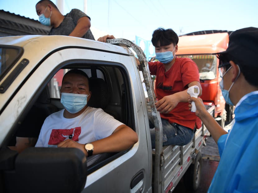 A security personnel wearing a protective suit checks the temperature of people entering the Xinfadi market in Beijing on June 14, 2020. The domestic outbreak in China had been brought largely under control through strict lockdowns that were imposed early this year — but a new cluster has been linked to Xinfadi market in south Beijing.