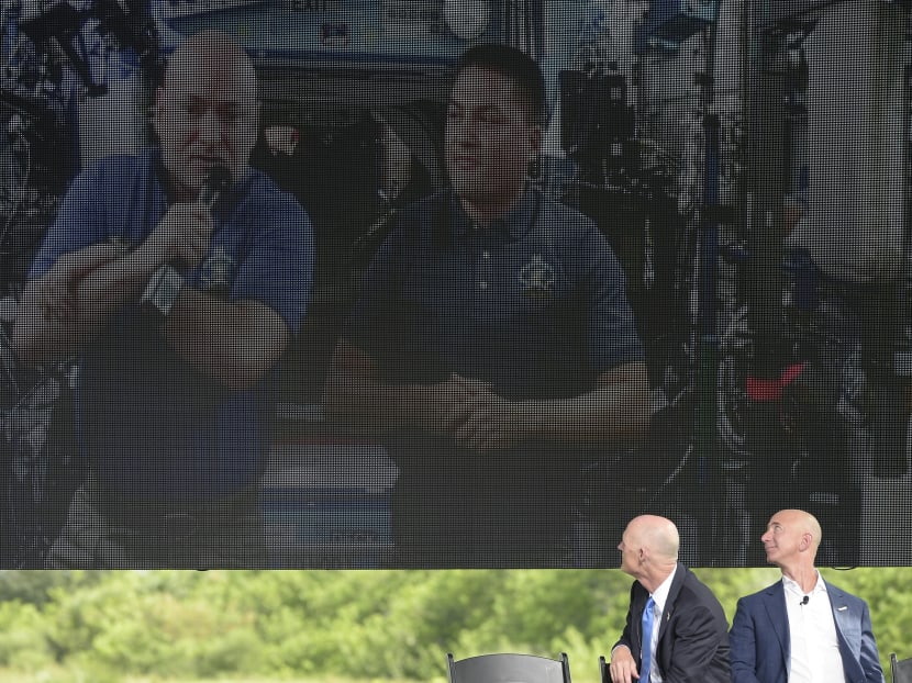 Amazon CEO Jeff Bezos, right, and Florida Governor Rick Scott watch a video message from Nasa astronauts Scott Kelly, left, and Kjell Lindgren, aboard the International Space Station, during a news conference in Cape Canaveral, Sept 15, 2015. Photo: AP