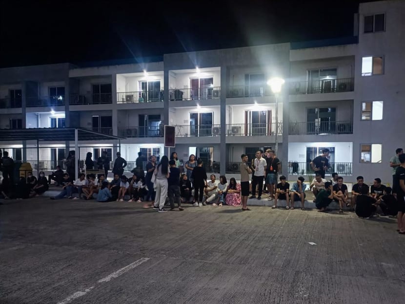 This handout photo taken on May 4, 2023 and received from the Philippine National Police anti-Cybercrime group on May 6 shows rescued trafficked people from Asian countries standing outside a building after a police raid inside a freeport zone in Mabalacat City, in Pampanga province, north of Manila. 