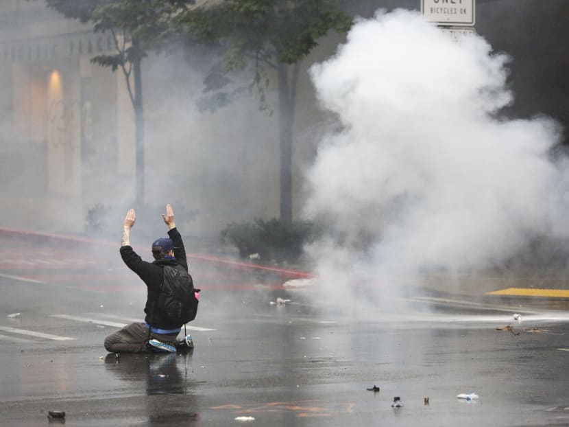 A protester kneels and holds his hands up as police use tear gas after protests against the death of George Floyd turned destructive in Seattle, Washington on May 30, 2020.