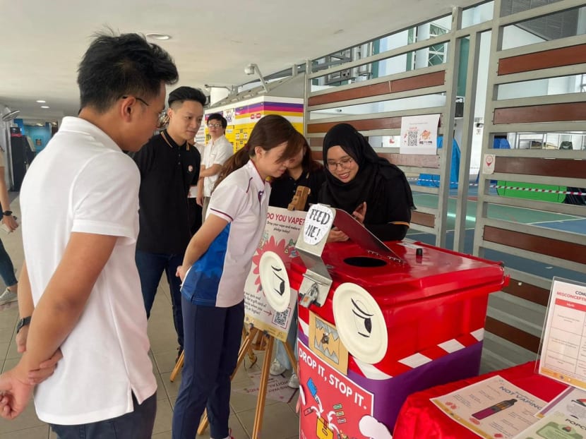 Member of Parliament Tin Pei Ling (second from left) peering into a collection box for e-vaporisers.
