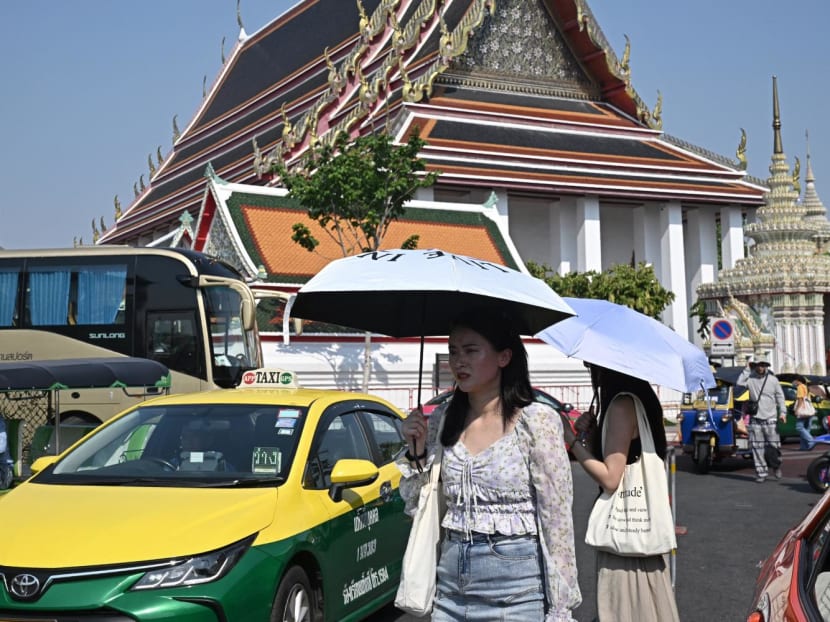 Tourists shield themselves from the sun with umbrellas to combat the heat outside Wat Pho Buddhist temple in Bangkok on April 1, 2024. Tourists shield themselves from the sun with umbrellas to combat the heat outside Wat Pho Buddhist temple in Bangkok on April 1, 2024.