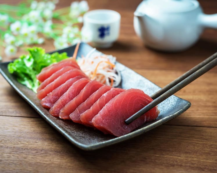 How do food outlets and delivery providers ensure that raw fish is safe to consume?