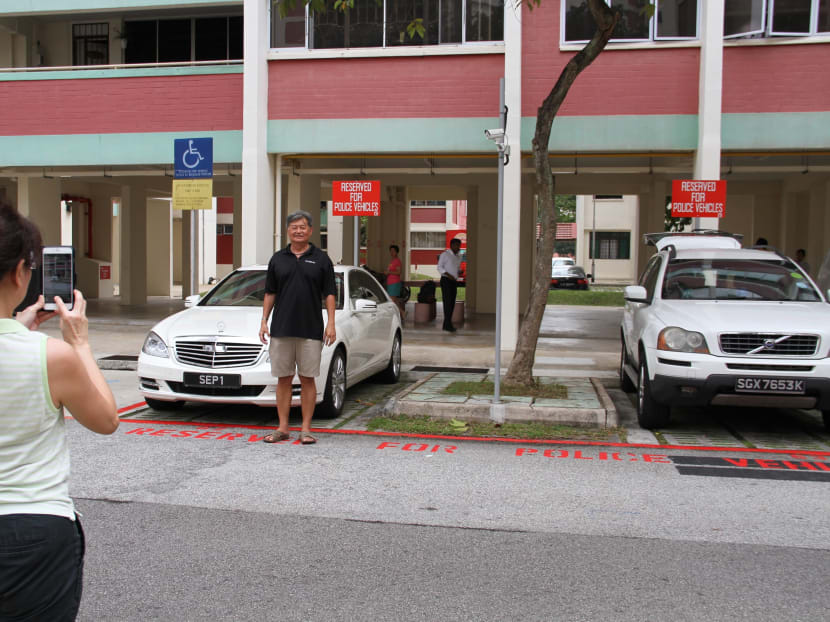 People posing with Madam Halimah Yacob's presidential car parked in a specially-marked lot at her public housing block in Yishun. Photo: Esther Leong/TODAY