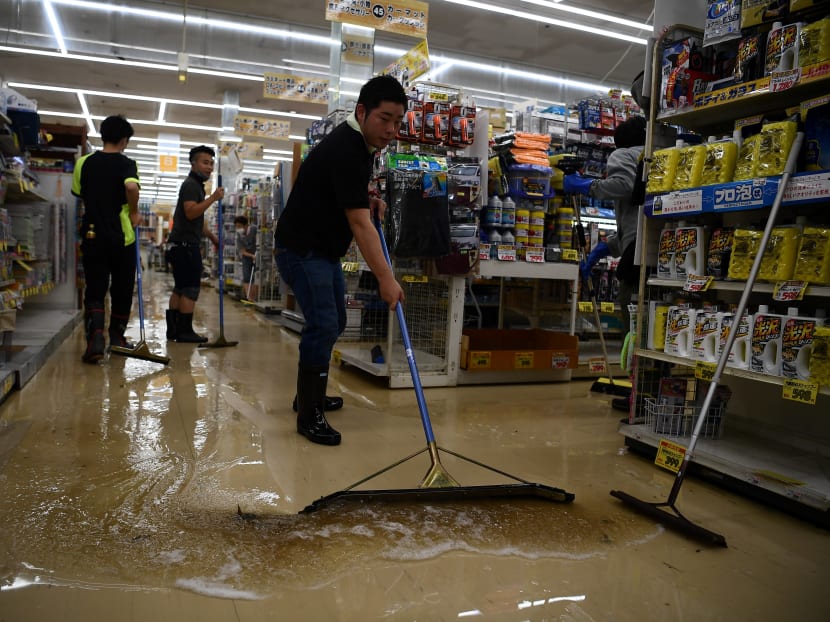 Employees clear flood waters from a store in Kurume, in Fukuoka Prefecture on July 8, 2020.