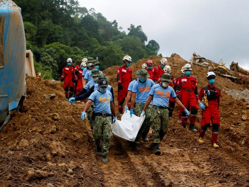 Police officers carry a body bag as search and rescue operations continue in the landslide-hit village of Masara, Maco, Davao de Oro, Philippines, on Feb 8, 2024. 