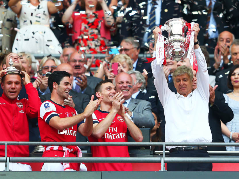 Arsene Wenger, manager of Arsenal,  lifts the trophy in celebration alongside Lukas Podolski,  Mikel Arteta and Thomas Vermaelen after the FA Cup with Budweiser Final match between Arsenal and Hull City at Wembley Stadium on May 17, 2014 in London, England. Photo: Getty Images