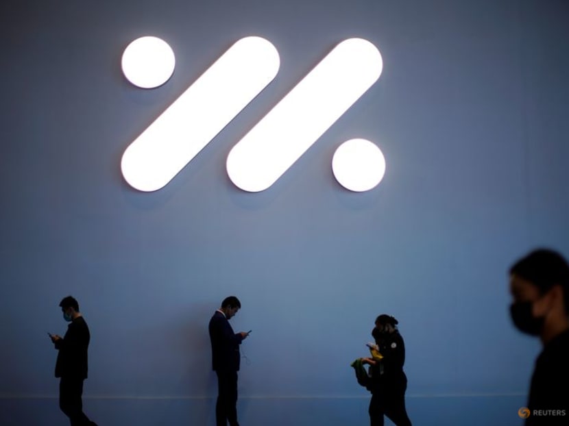 People stand under the logo of IM Motors, an electric vehicle (EV) brand jointly founded by SAIC Motor, Zhangjiang Hi-Tech and Alibaba Group, during a media day for the Auto Shanghai show in Shanghai, China April 19, 2021. REUTERS/Aly Song/file photo