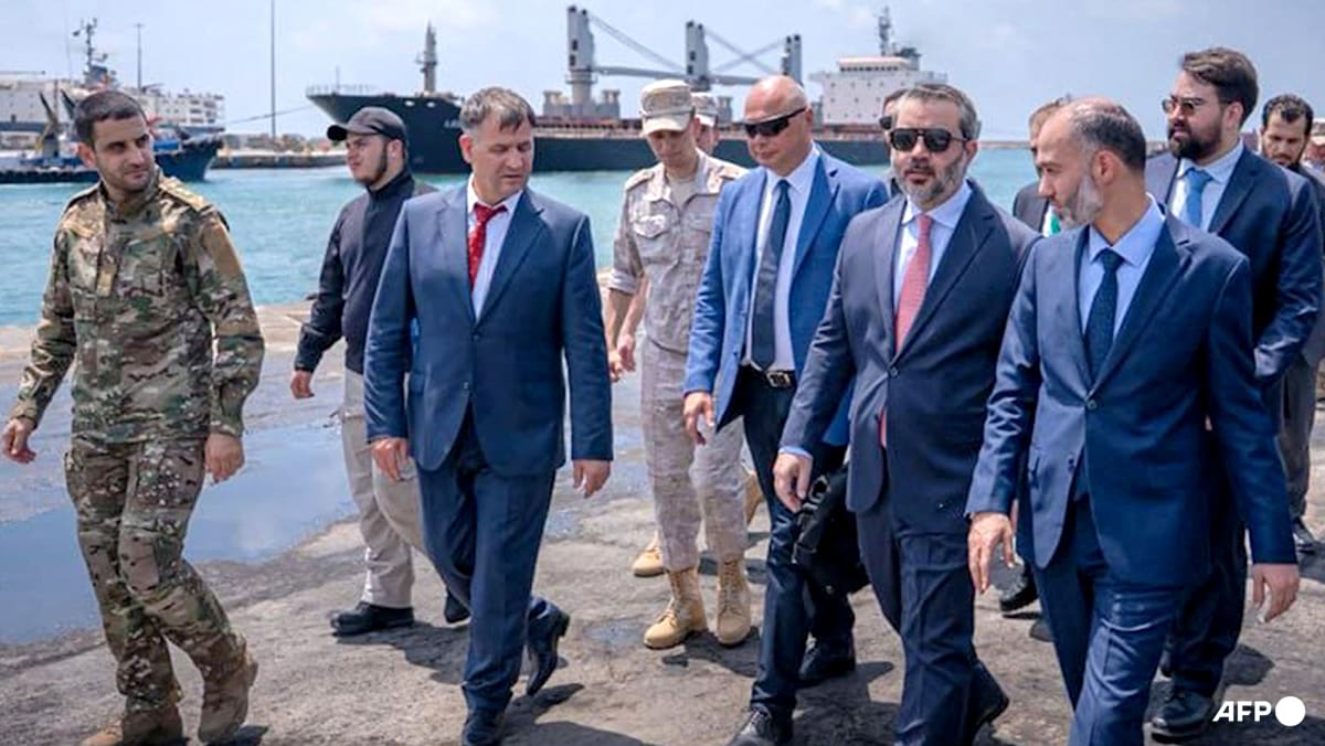 A group of men in suits and military uniforms walking on a pier next to a ship.