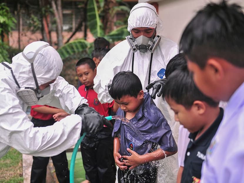 Pupils from a school in Pasir Gudang being washed and cleaned after chemicals were dumped into Sungai Kim Kim last week.