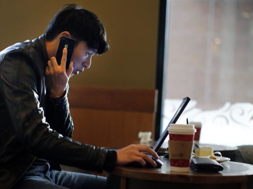 A man talks on the phone as he surfs the internet on his laptop at a coffee shop in a Nov 28, 2013 file photo. Photo: Reuters