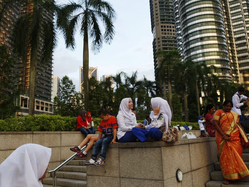 Women talk in front of the Petronas twin towers in Kuala Lumpur. Malaysia’s millennials are forced to continue living with their parents because of low wages and high inflation. Photo: Reuters