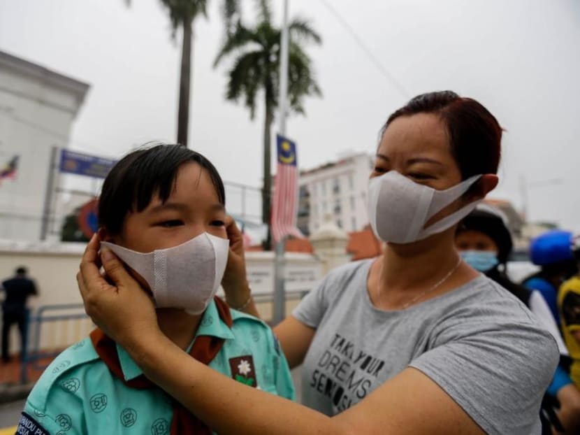 A student covers her face with a mask outside a school in George Town Sept 18, 2019.
