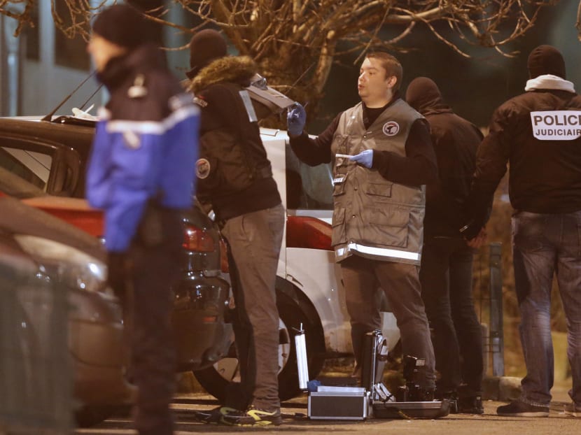 Police investigators search for evidence as an unidentified man is detained (2nd R) during an operation in the eastern French city of Reims. Photo: Reuters