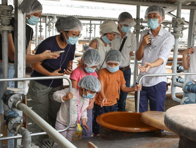 A guide explaining the soy sauce production process to participants at the Tai Hua soy sauce factory on July 26, 2024. 