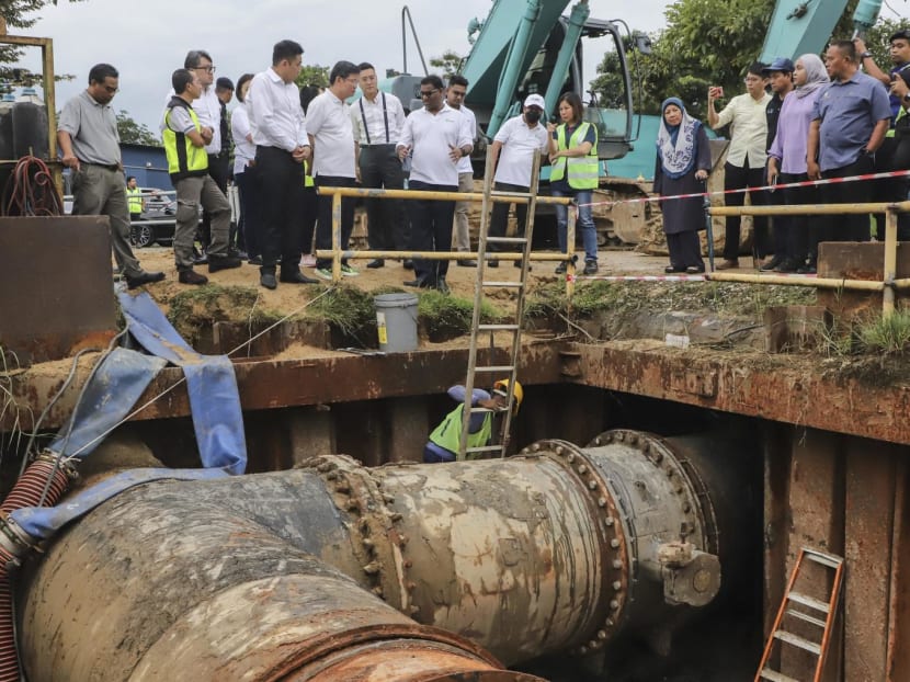 Workers replace water valves at the Sungai Dua water treatment plant as Penang's Chief Minister Chow Kon Yeow (top centre L) inspects their progress in Penang on Jan 10, 2024. 