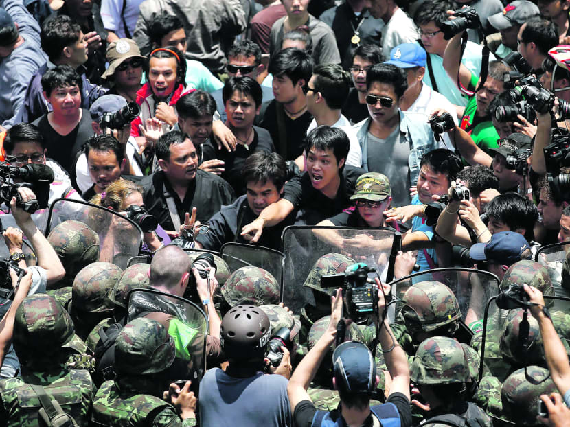 Thai anti-coup protesters and soldiers confront each other in Bangkok yesterday. The Thai military tightened its grip on power as it moved to rally commercial agencies and business to revitalise a battered economy, while the US cancelled military exercises with Thailand and suspended S$4.4 million in military aid. Photo: Reuters