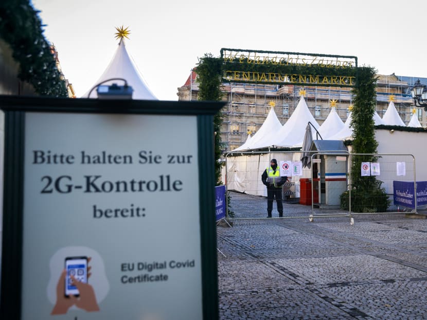 A sign telling people to keep their vaccination pass or recovered status ready for inspection is seen as a security guard mans the gate prior to the opening of the Gendarmenmarkt Christmas market in Berlin on Nov 22, 2021.