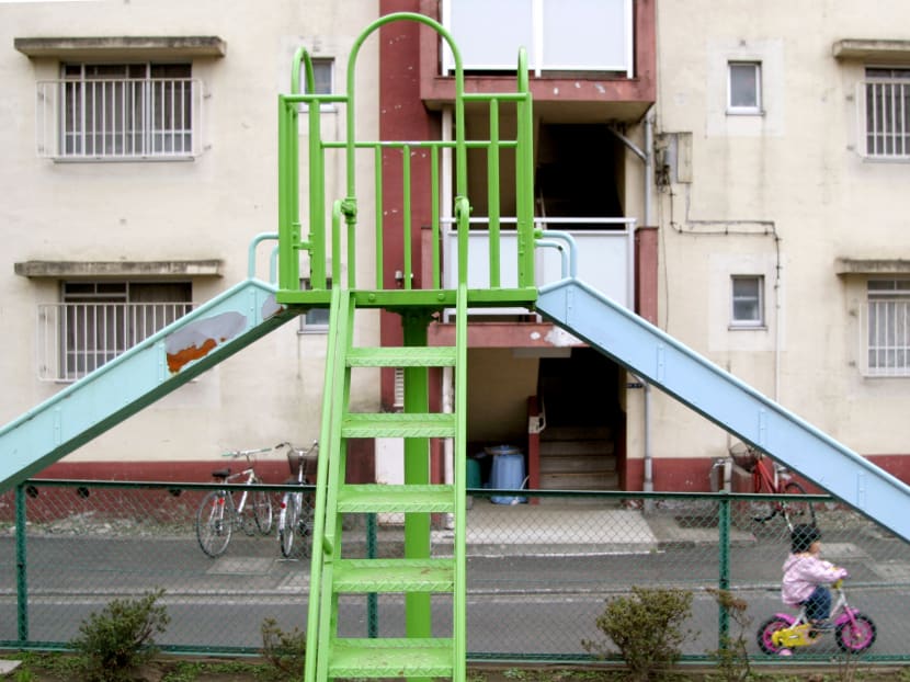 A child cycles past a metal slide at a public playground park in central Tokyo, Japan, March 15, 2007. Photo: Bloomberg