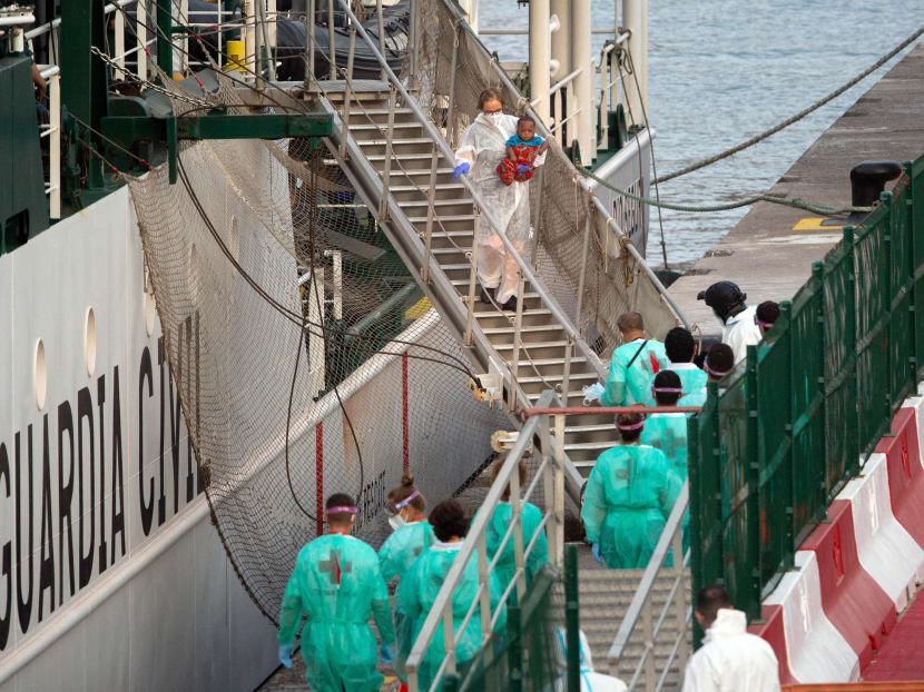 A woman holds a baby of a group of 41 migrants upon their arrival in Puerto De Los Cristianos onboard a Civil Guard vessel in Arona, on the Spanish Canary island of Tenerife on April 27, 2021. They were found on a boat south of the island of Gran Canaria.