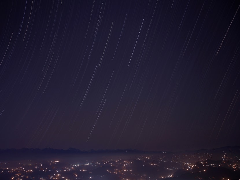 A long exposure picture shows a star trail above the mountain range during the Geminid meteor shower celestial event in Nepal.