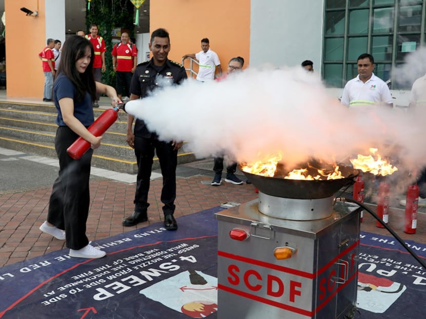 Writer Eveline Gan putting out a fire during a hands-on training session under the Community Emergency Preparedness Programme on May 5, 2023. 