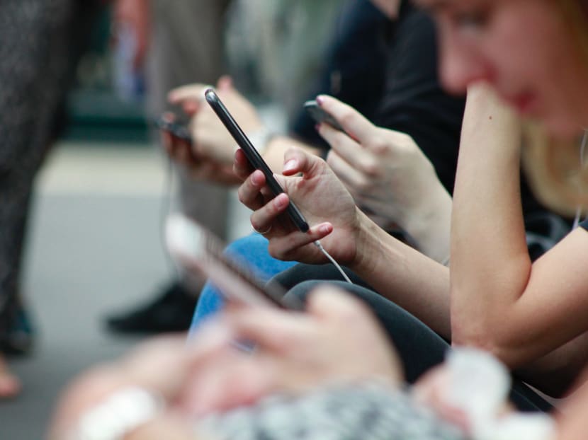 People scroll through their phones in Bath, England.