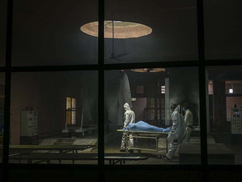 Ambulance staff wearing personal protective equipment suits carry the dead body of a person who died due to Covid-19 inside a crematorium in New Delhi, India on May 21, 2021. Ambulance staff wearing personal protective equipment suits carry the dead body of a person who died due to Covid-19 inside a crematorium in New Delhi, India on May 21, 2021.