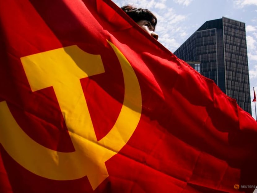 FILE PHOTO: A woman holds a flag of the Communist Party of China as she poses for a picture during an exhibition at the Memorial of the First National Congress of the Communist Party of China, ahead of the 100th founding anniversary of the party, in Shanghai, China June 22, 2021.  REUTERS/Aly Song/File Photo