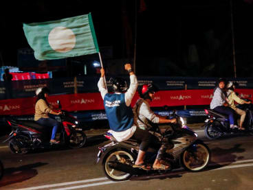 A pillion waves a PAS flag on the eve of Malaysia's general election at Permatang Pauh, Penang, Malaysia on Nov 18, 2022. 