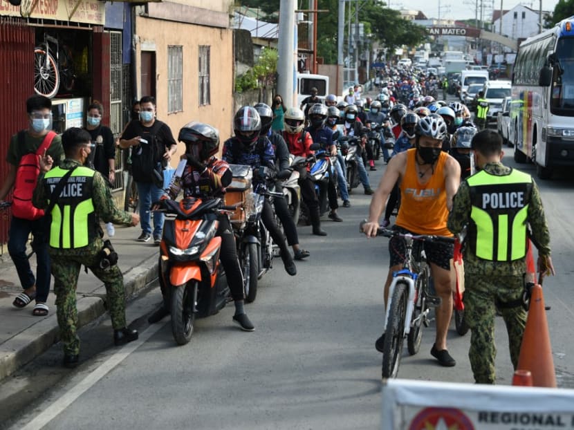 Policemen check documents of motorists at a border check point in Marikina City, suburban Manila on August 6, 2021, after authorities imposed another lockdown to slow the spread of the hyper-contagious Delta variant and ease pressure on hospitals while trying to avoid crushing economic activity.