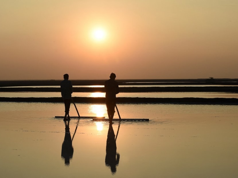 This picture taken on Jan 8, 2021 shows labourers working on a salt pan as the sun sets at the Little Rann of Kutch region near Kharaghoda village, some 150 km from Ahmedabad.