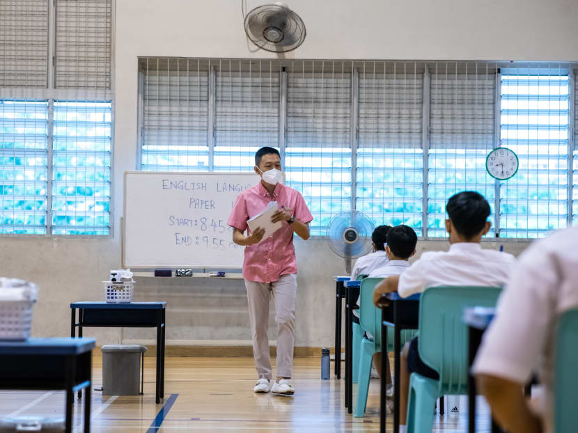 An invigilator distributes the examination papers in the examination venue for students taking leave from quarantine.